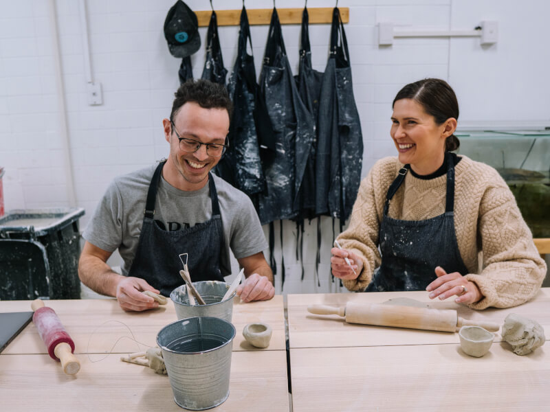 A man and woman making pottery at a craft class.